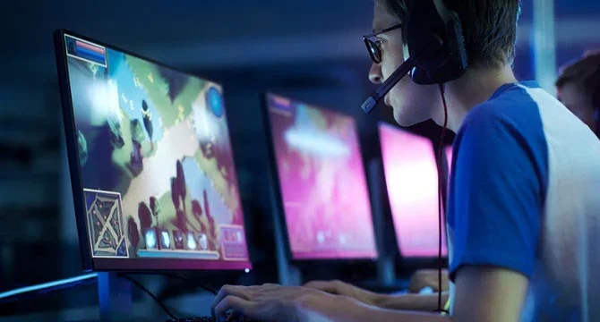 jonge gamer met een headset die een videogame speelt op een desktopcomputer
